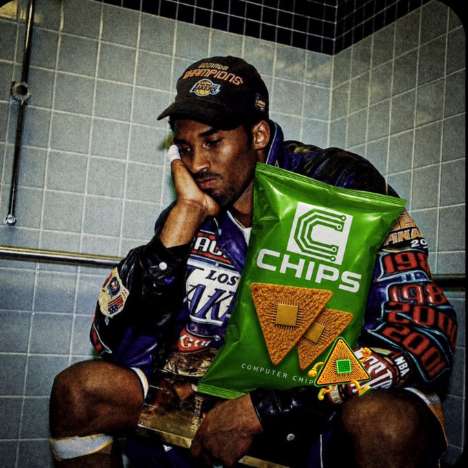 A person wearing a Lakers 'Champions' cap and a jacket covered in championship patches sits in a tiled bathroom holding a green bag of 'C Chips Computer Chips' snacks.