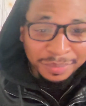 A close-up selfie shows a man with glasses and facial hair wearing a dark hooded jacket.