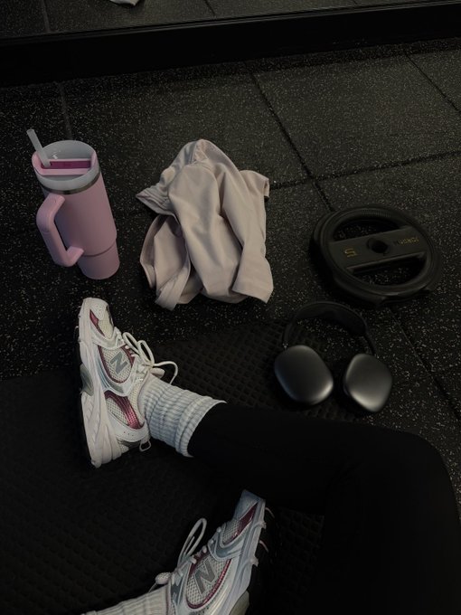 The image features a person's feet resting on a black surface with various fitness-related items placed around them, including a pair of sneakers, headphones, and workout equipment such as dumbbells or kettlebells. The presence of these items suggests that the person is engaged in some form of exercise or physical activity. The post about Aptos and its self-custodial financial system seems unrelated to this scene but could be related to fitness or personal finance if there are any connections between them.