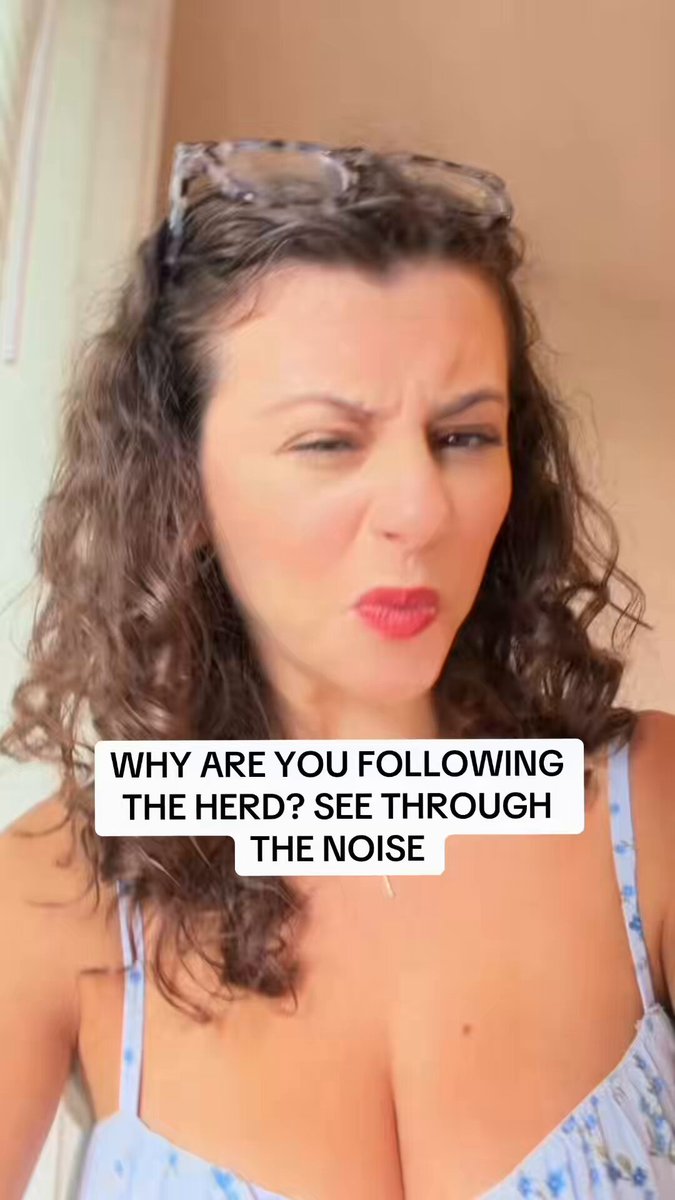 The image features a woman with curly hair wearing glasses and a blue dress. She has her eyes closed and appears to be making a funny face for the camera. The caption of the image reads, "Why are you following the herd? See through the noise". This statement is related to Bitcoin, as it suggests that people should not follow trends blindly but instead focus on understanding the underlying technology and making informed decisions about investing in cryptocurrency.
