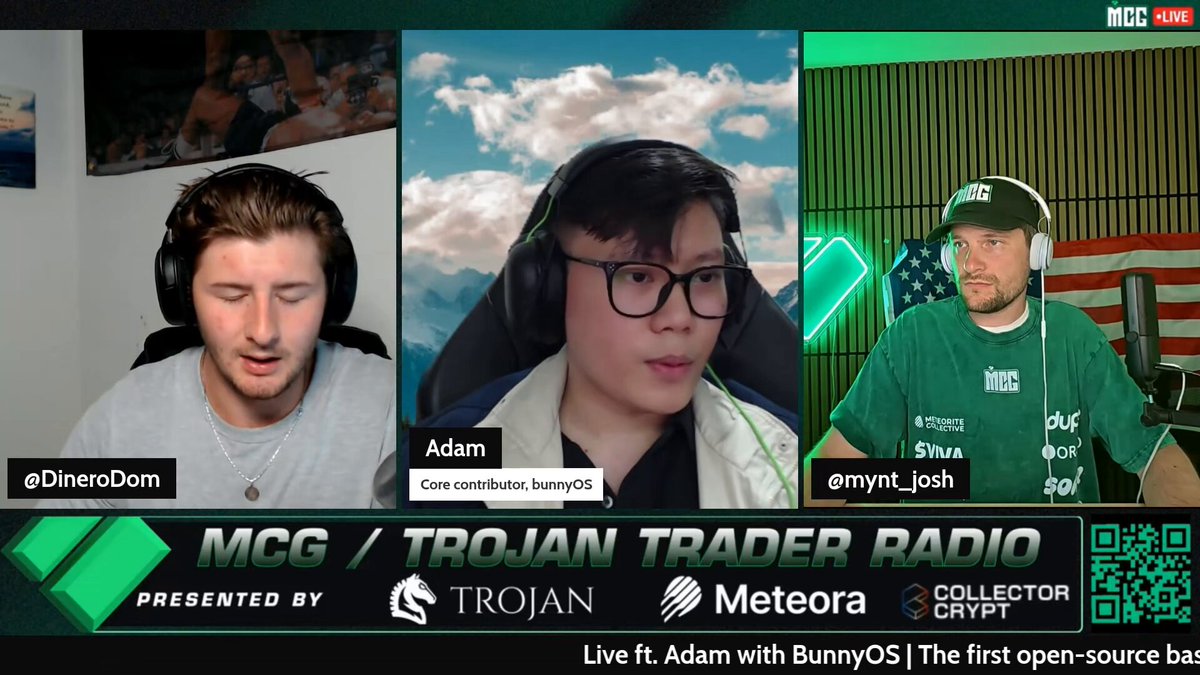 The image shows a group of three people sitting behind microphones, appearing to be participating in an online radio show or podcast. The hosts are wearing headphones, which suggests that they might be discussing a topic related to cryptocurrency or financial markets. The background features a green wall with a picture and text elements, possibly providing information about the show's sponsors or topics being discussed.