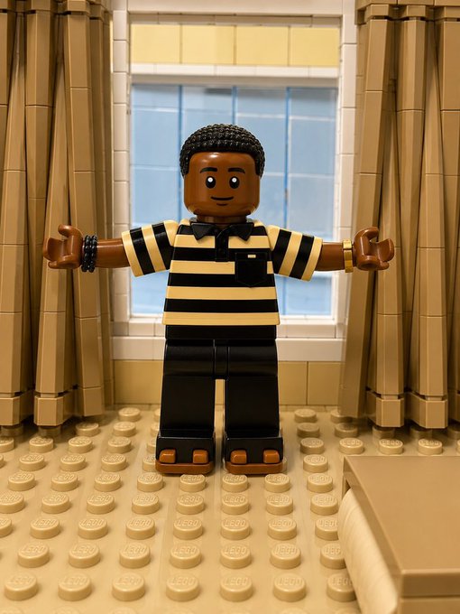 A Lego-style minifigure character with a striped shirt and bow tie stands in a T-pose on a studded floor between curtains in a room setting. The image appears to be used as a playful, blocky avatar or visual representation in a social media post celebrating milestones related to "$ANSEM" and bullposting growth.