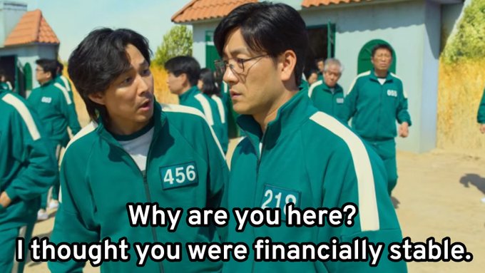 A scene from the TV show Squid Game showing contestants 456 and 219 in green tracksuits, with subtitles reading 'Why are you here? I thought you were financially stable.'