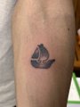 The image shows a small lotus flower tattoo on someone's forearm. While the caption mentions trading on OpenSea and references @opensea, there is no visible text, ticker, or trading-related content in the image—just the minimalist lotus ink on skin.