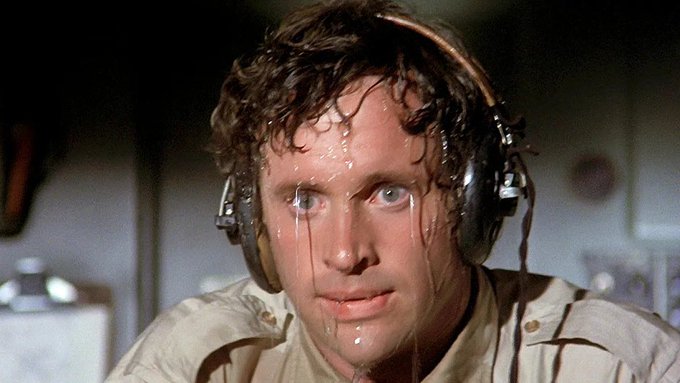 A sweaty, wide-eyed man wearing headphones stares intensely toward the camera, captured in what appears to be a tense scene from the film *The Big Lebowski*. The image humorously conveys the shock and adrenaline of witnessing a massive market rebound after a prolonged downturn, with his nervous expression perfectly capturing the "strap in" energy of the post.