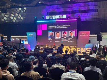 A view from the audience at a large indoor conference labeled 'MYBUYG', showing attendees seated in rows facing a brightly lit stage where a panel discussion titled 'Indonesia's Tokenized Deposits and the Future of Settlements' is taking place.