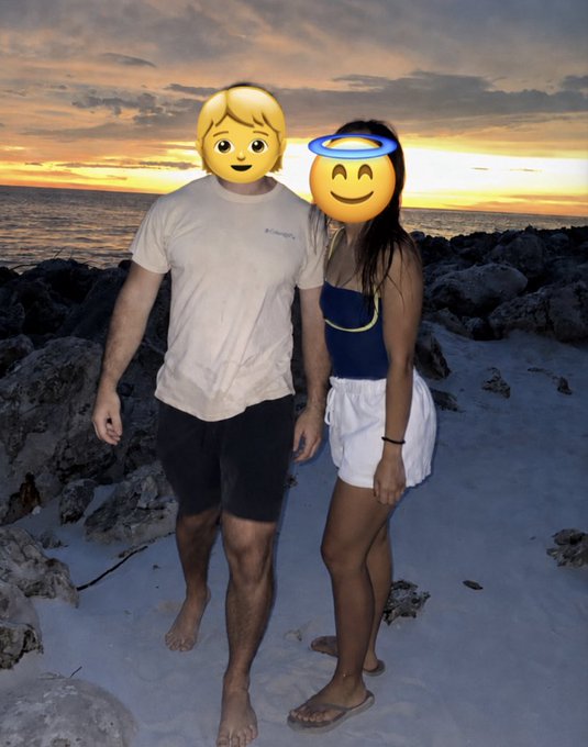 A photo of a couple standing on a rocky beach at sunset, with their faces covered by blonde and haloed smiling emoji stickers.