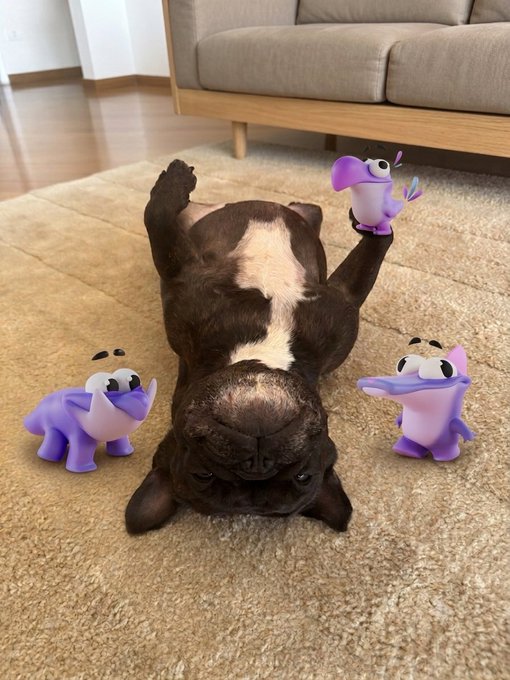 A French bulldog lies upside down on a beige rug with three digitally added purple cartoon creatures surrounding it, while a beige couch sits in the background.