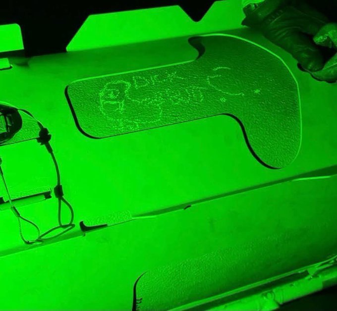 An image bathed in intense green light showing a textured surface with the letters 'BULK' etched into it, alongside a pair of glasses and other objects.