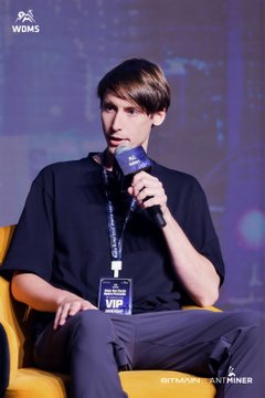 A young man in a black t-shirt speaks into a microphone while seated on a yellow chair; the image bears 'WGNS' watermark in the top left and 'GETTY IMAGES / RYAN VINNER' in the bottom right.