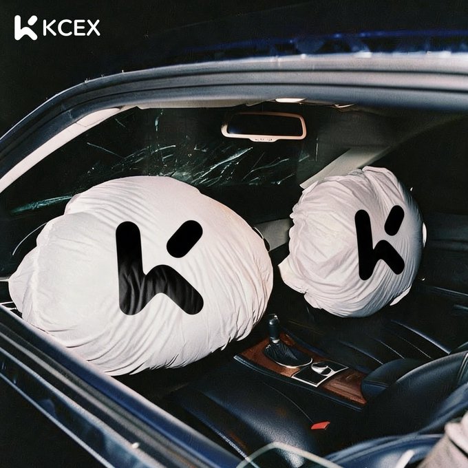 A dark car interior showing deployed white airbags with a stylized 'K' logo printed on them, branded with 'KCEX' in the upper left corner.