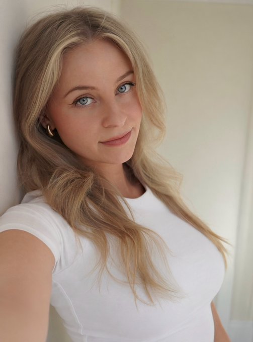 A young blonde woman in a white t-shirt looks directly at the camera, possibly signaling confidence or consideration before making a decision. The image pairs with the post "Might buy some ADA later," suggesting she represents a thoughtful potential investor evaluating a purchase of Cardano cryptocurrency.