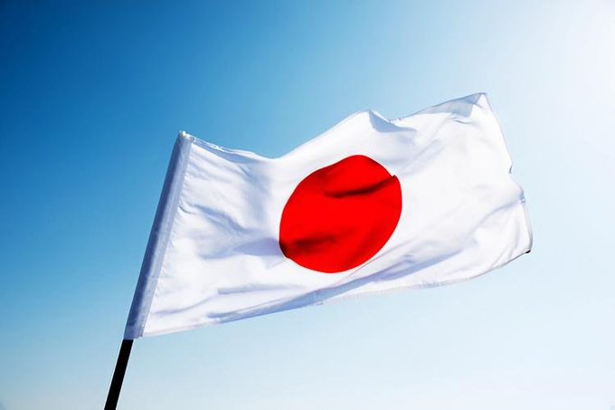 The Japanese flag waves against a clear blue sky, symbolizing the nation's latest regulatory push to combat crypto scams through proposed temporary withdrawal delays on new purchases and wallet registrations. The flag's bold red sun on a white field represents Japan's commitment to strengthening investor protection in the cryptocurrency space.