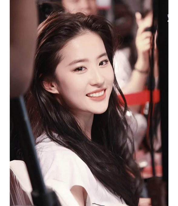 A young woman with long dark hair smiles warmly at the camera while wearing a white top, posing in what appears to be a studio or event setting. The caption "My name is Da Mei Una" suggests this is a personal introduction post, with the image showcasing her friendly, approachable demeanor.