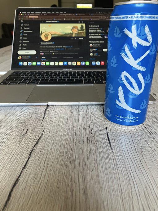 A can of 'Koia' sparkling water sits on a wooden table in front of an open MacBook Pro laptop displaying what appears to be a Discord application.