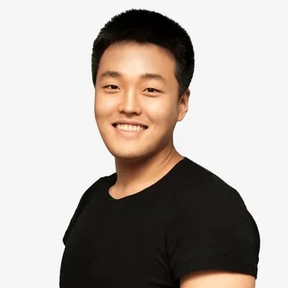 A smiling young Asian man with short black hair wearing a black t-shirt against a plain white background.