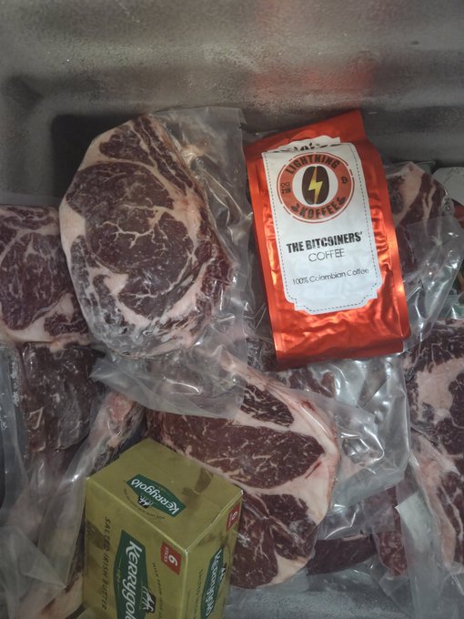 A package containing multiple vacuum-sealed steaks alongside a red bag of "The BitGainers' Coffee" (100% Colombian Coffee) and a green Keerrigon tea box.