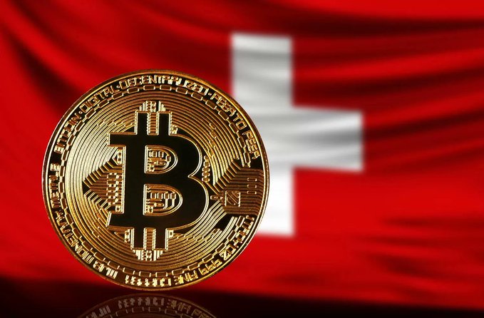 A close-up of a gold Bitcoin coin displayed against a red Swiss flag with a white cross in the background.