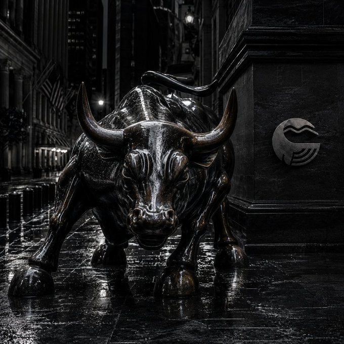 A black and white image shows the bronze Charging Bull statue standing on a wet city sidewalk at night, with a stylized wave logo plaque mounted on the wall to its right.