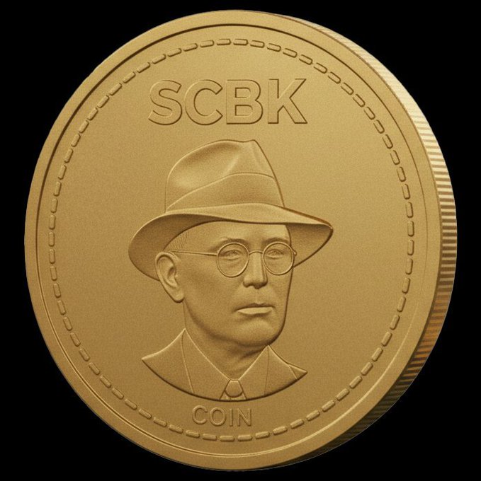 A close-up of a gold-colored commemorative coin featuring a portrait of a man wearing a hat and round glasses, with the text 'SCBK' at the top and 'COIN' at the bottom.