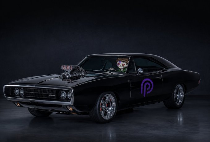 A black muscle car (Dodge Charger) with a Joker character behind the wheel and a purple PolitiFi-style logo on the door, set against a dark background.