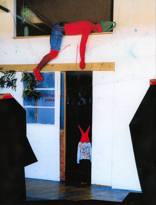 An art installation featuring a figure dressed in red and denim draped over a high ledge, above a doorway displaying a blue dress, set against a backdrop with 'PRIMARY' and 'BUREA' text.