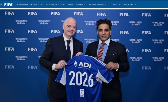 FIFA President Gianni Infantino and another man in suits pose together at a FIFA 'Football Unites the World' event, holding up a blue jersey reading 'ADI Pakistan 2026'.