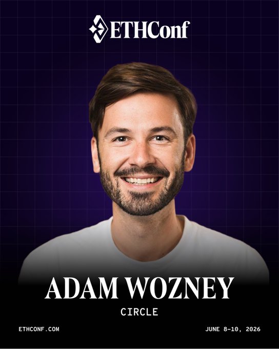 The image features a man with a beard wearing a white shirt smiling for the camera. The background of the image is purple, which contrasts with the man's white shirt. There are also some text elements present in the image that read "@Adam Dean Wozney" and "@Circle A".