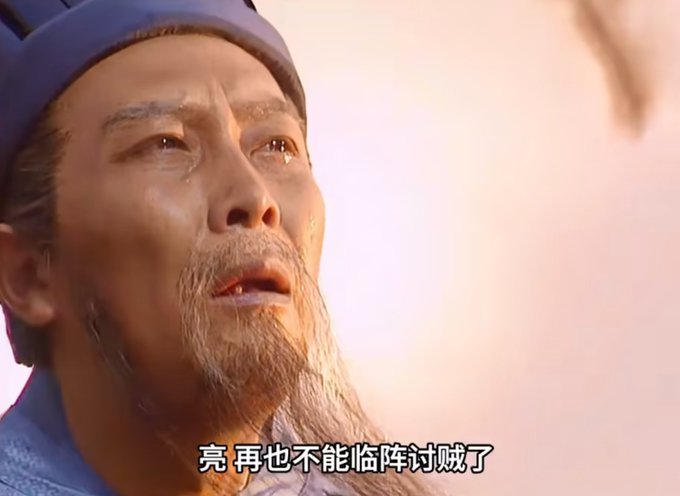 A close-up shot from a film shows an older bearded man with tears in his eyes, with Chinese subtitles reading '亮 再也不能临阵讨贼了'.