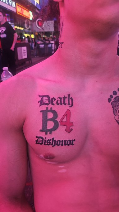 A shirtless person displays a prominent "Death Before Dishonor" tattoo on their chest, with "B4" styled as the Bitcoin Cash (BCH) logo, photographed in the neon-lit ambiance of Times Square during NFT NYC. The tattoo cleverly merges the motto's "Before" with BCH branding, tying into the post's theme of BCH "Proof of Work" promotional campaigns in the area.