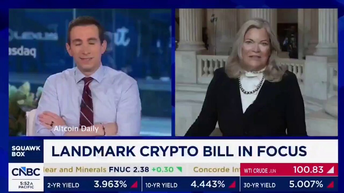 The image shows a news broadcast with two people, one man wearing a tie and another woman dressed in black, standing behind a desk. They are both talking about a bill called Landmark Crypt Bill that has been introduced by Aloin Dally. The news anchor is discussing this bill on the news show.
