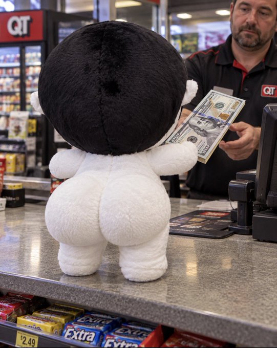 A plush doll standing at a QT convenience store counter, appearing to hand a fifty dollar bill to a store clerk.