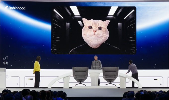 A Robinhood event stage featuring a massive screen displaying a cat head with a man's body, while presenters stand on the futuristic white stage below.