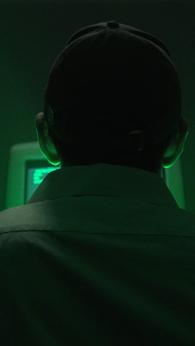 The image shows a person wearing a black baseball cap, looking at a computer screen with green lights coming from behind them. The background appears to be dark, which emphasizes the focus on the person's face and the computer screen. The caption suggests that this photo was taken during the month of June 1st, possibly as part of an online challenge or event related to Cicada.