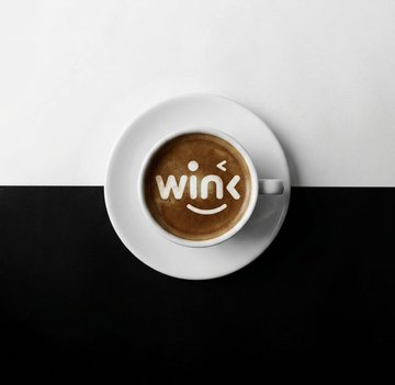 A steaming cup of coffee with the "wink" logo and a smiley face adorns a black and white surface, symbolizing a positive and engaging experience in decentralized systems. This graphic visually represents the reliability and integrity desired in oracle networks.