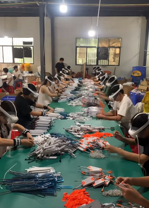 Workers wearing VR headsets sit along a long assembly table in a Chinese factory, assembling and packaging various cables and electronic components, illustrating the AI-driven data collection and robot training industry mentioned in the post, where workers earn 40-80 yuan per hour.