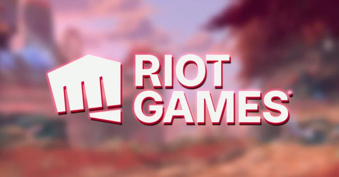 The Riot Games logo displayed prominently over a blurred, warm-toned fantasy game environment background.