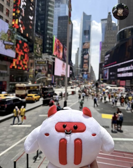 The image features a white stuffed animal with red eyes and horns standing out against a city backdrop. The stuffed animal appears to be holding up a sign that says "ETHGlobal Week is always the gathering place for the most dynamic builders, developers, and projects in the Web3 space And this year, TRON is making its presence felt in its very own unique way Tonight, TRONAcademy will welcome the student community, developers, and". The stuffed animal's position on a city street with cars and people suggests that it might be promoting an event or cause related to cryptocurrency or web3.
