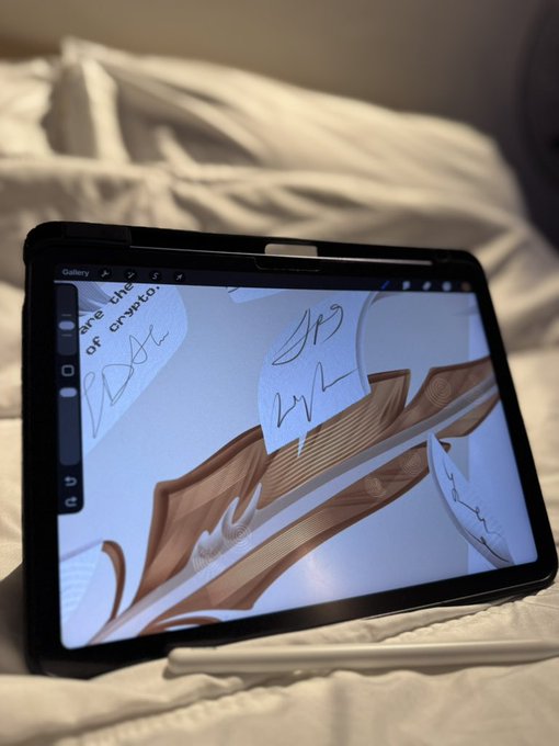 A tablet displaying digital artwork of a sword rests on a bed, with a stylus placed beside it.
