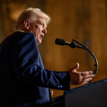 President Donald Trump is captured mid-speech at a podium with a microphone, his hand raised expressively. The accompanying post suggests the image accompanies news of his reported selection of Jay Clayton, former SEC chair, as the White House's new AI czar.