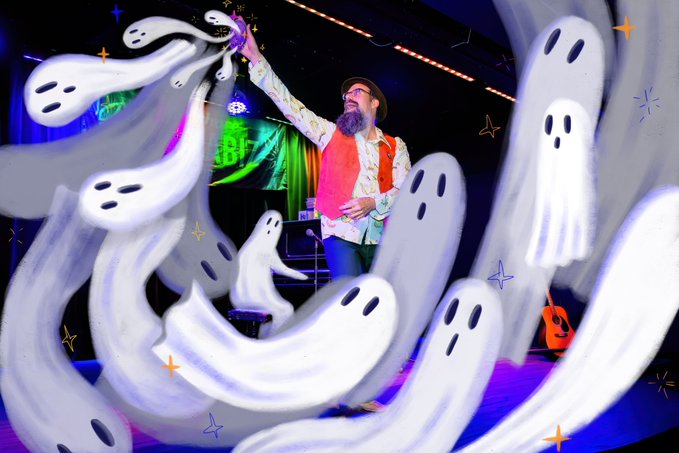 A man with a beard and hat performs on a colorful stage, surrounded by swirling, digitally-added cartoon ghosts and stars.