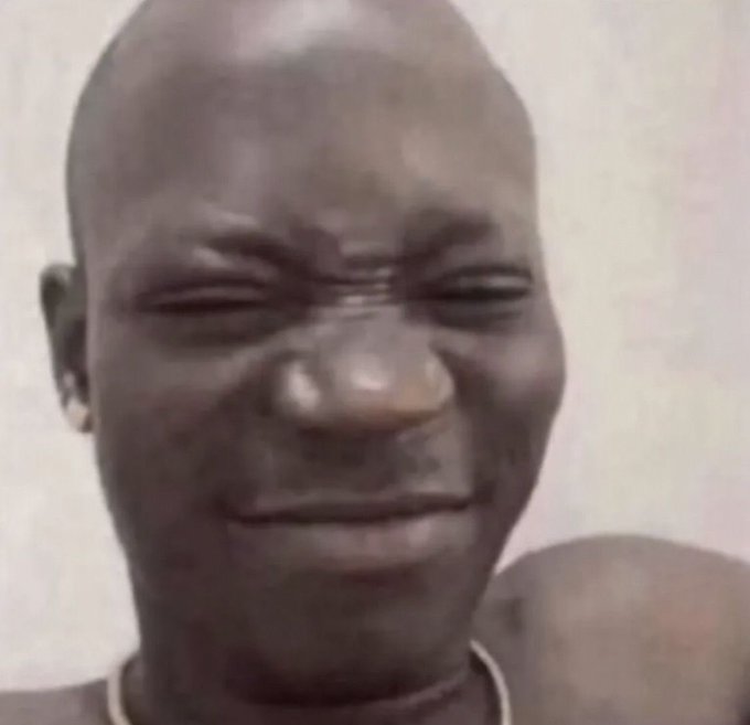 The image shows a bald young person with a tearful, distressed expression, appearing to cry while smiling awkwardly. The meme humorously pairs with the caption about a "newbie" investing their last $5 at a market top, using the emotional face to depict the helplessness and regret of traders learning hard lessons in the "trenches."