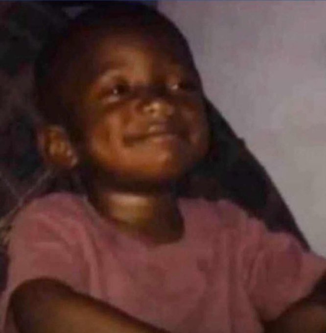 A blurry, low-quality meme image of a young child smiling while looking off to the side, wearing a pink shirt.