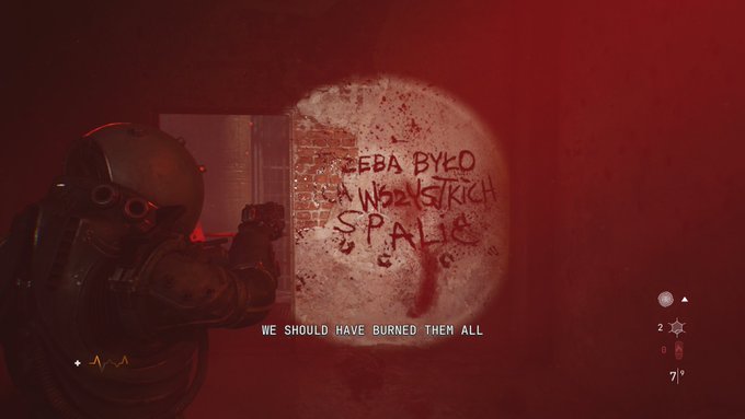A dark, red-tinted scene from a video game showing a tactical operator aiming at graffiti on a brick wall that reads 'ZEBABYL ON A WOODSTICK SPACE 9', with subtitle text stating 'WE SHOULD HAVE BURNED THEM ALL'.