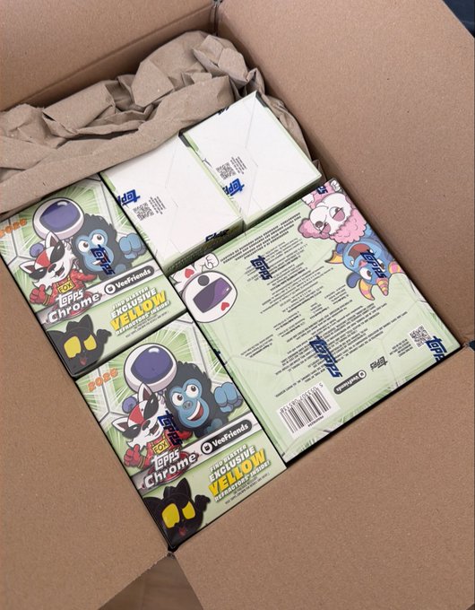 An open cardboard shipping box contains several sealed Topps Chrome Yellow 2025 Hobby trading card boxes, including Walmart exclusive variants, packed with crumpled brown packing paper.