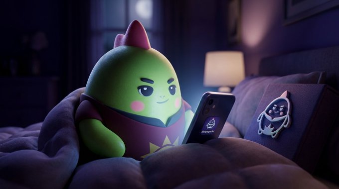 A 3D animated green blob-like character lies in bed under a blanket, illuminated by the glow of a smartphone screen, with a dark plush toy beside it.