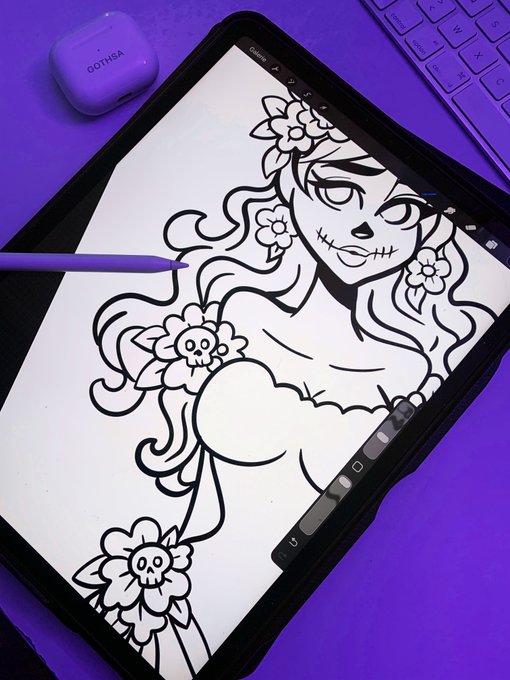 A digital drawing on a tablet screen depicts a stylized female figure with skull-adorned flowers in her hair, drawn with a stylus on a purple surface.
