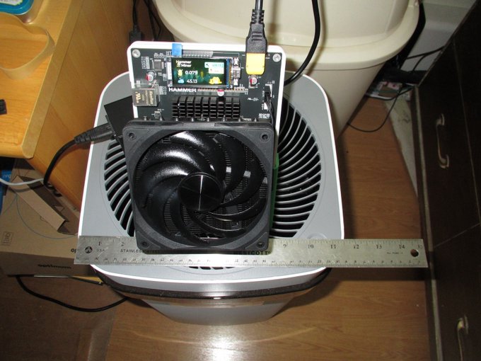 An electronic device setup featuring a HAMMECH component board with a digital display, a cooling fan, and a metal ruler laid across it for scale measurement.