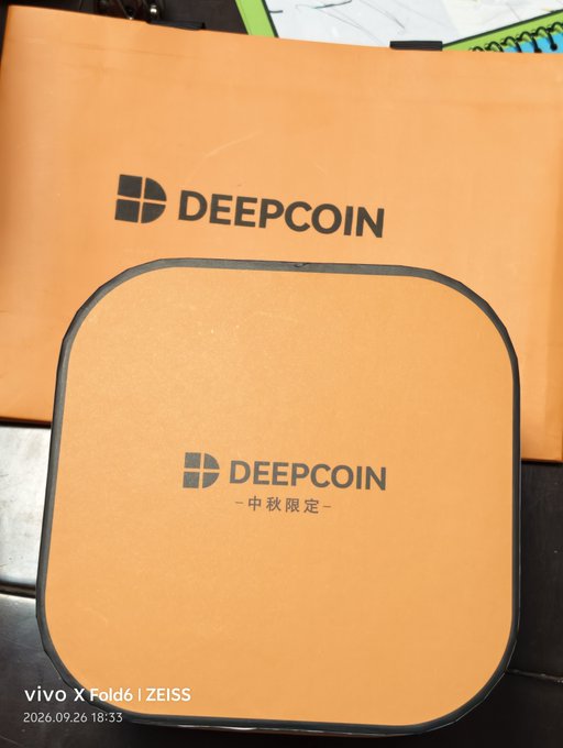 A person proudly displays a limited edition Mid-Autumn Festival gift box from DeepCoin, featuring the brand's orange packaging with their logo and "中秋限定" (Mid-Autumn Limited) text, expressing gratitude for the thoughtful crypto community gift.