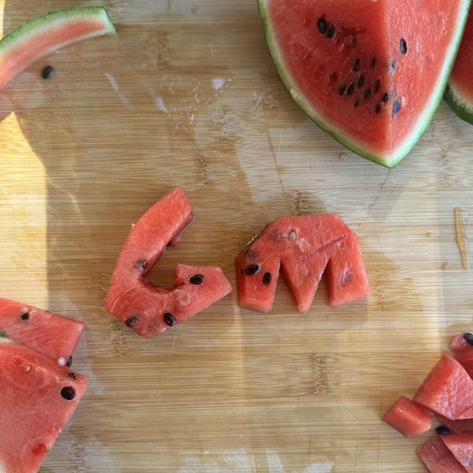 Pieces of watermelon cut into shapes on a wooden cutting board, with one piece resembling the TikTok logo.